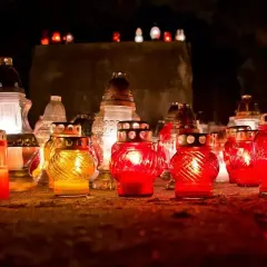 Płonące znicze na grobach, tworząc nastrój zadumy i pamięci. W ciszy wieczoru rozbrzmiewa ciche Ave Maria na pogrzebie.