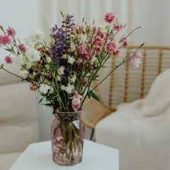 Kolorowy bukiet polnych kwiatów w różowym wazonie, jak z kwiaciarni, ozdabia wnętrze.