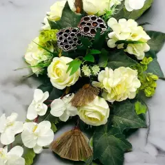 Eleganckie kompozycje funeralne z białych róż, storczyków i ozdobnych łusek lotosu na marmurowym tle.