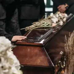 Dłoń na trumnie, kwiaty i suche trawy. Zastanawiasz się, ile trwa różaniec za zmarłego?