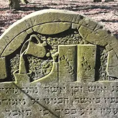 Kamienie na macewach symbolizują pamięć i szacunek. Na tej macewie widzimy symbol księgi, co może oznaczać mądrość lub Torę.