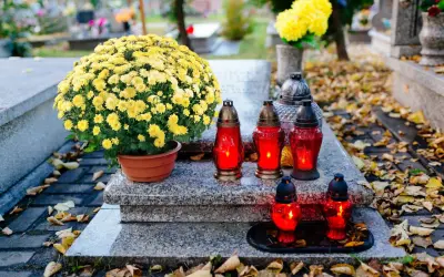 Na grobie bujne żółte chryzantemy, symbolizujące pamięć i szacunek. Płonące znicze dodają powagi.