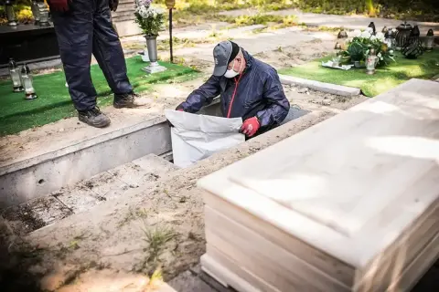 Pracownicy na cmentarzu przygotowują grób do ekshumacji. Co to jest? To proces wydobywania zwłok z ziemi.