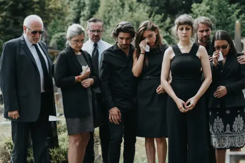 Żałobnicy w czerni, niektórzy płaczą. To smutne wydarzenie, być może pogrzeb świecki, co oznacza brak obrzędów religijnych.