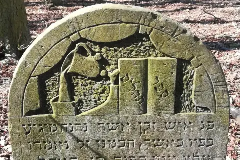 Kamienie na macewach symbolizują pamięć i szacunek. Na tej macewie widzimy symbol księgi, co może oznaczać mądrość lub Torę.