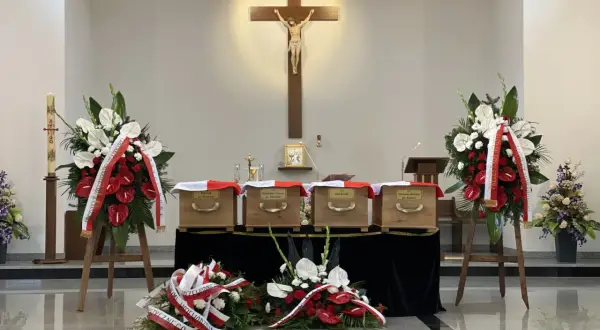 Msza pogrzebowa krok po kroku: cztery trumny, krzyż, znicz i wieńce.