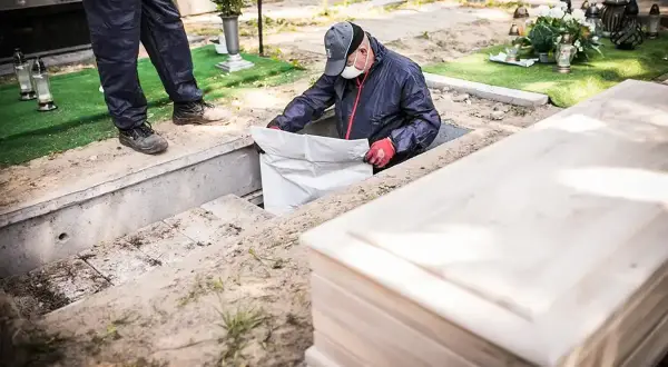 Pracownicy na cmentarzu przygotowują grób do ekshumacji. Co to jest? To proces wydobywania zwłok z ziemi.