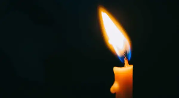 Płonąca świeca w ciemności. Symbolizuje smutek i tęsknotę, jak w cytatach o święta bez bliskiej osoby.