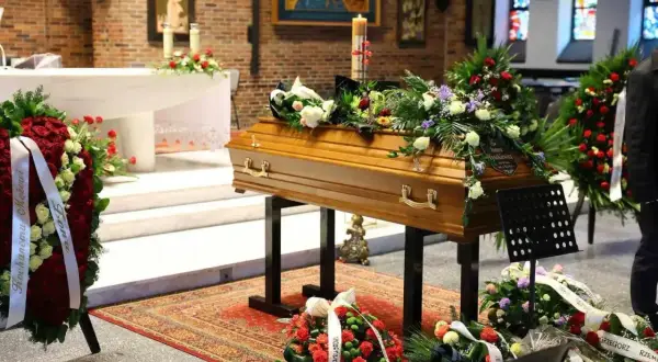 Drewniana trumna ozdobiona kwiatami w kaplicy, symbol pożegnanie zmarłego.
