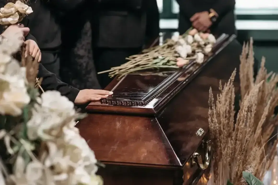 Dłoń na trumnie, kwiaty i suche trawy. Zastanawiasz się, ile trwa różaniec za zmarłego?