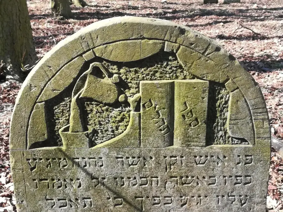 Kamienie na macewach symbolizują pamięć i szacunek. Na tej macewie widzimy symbol księgi, co może oznaczać mądrość lub Torę.