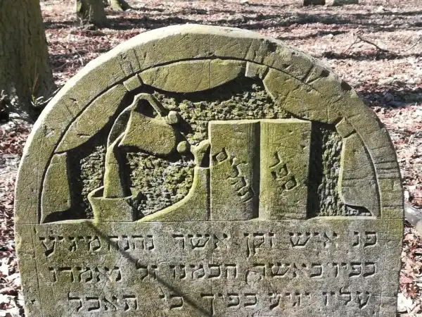 Kamienie na macewach symbolizują pamięć i szacunek. Na tej macewie widzimy symbol księgi, co może oznaczać mądrość lub Torę.